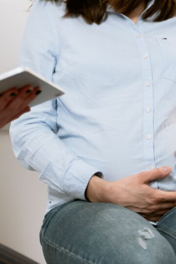 Pregnant woman attending a healthcare consultation, showcasing doctor-patient interaction.