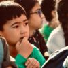 Focused child in a group of peers, pondering during an event