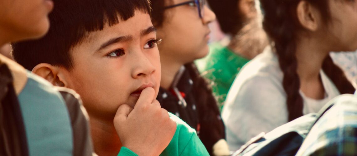 Focused child in a group of peers, pondering during an event