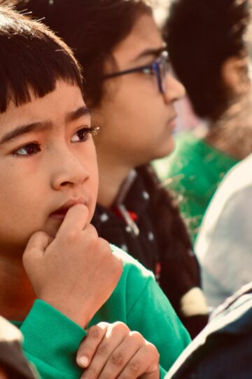 Focused child in a group of peers, pondering during an event