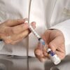 Veterinarian preparing a syringe with vaccine from a vial in a medical setting.