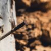 Detailed view of a rusty nail protruding from weathered wood, showcasing texture and age.
