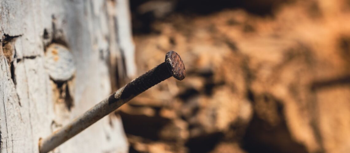Detailed view of a rusty nail protruding from weathered wood, showcasing texture and age.