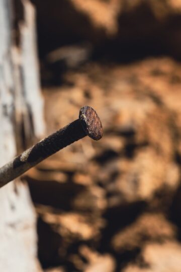 Detailed view of a rusty nail protruding from weathered wood, showcasing texture and age.
