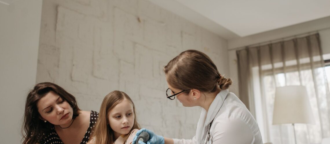 Mother and daughter consult with doctor about child vaccination in a medical office.