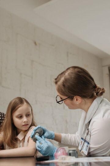 Mother and daughter consult with doctor about child vaccination in a medical office.