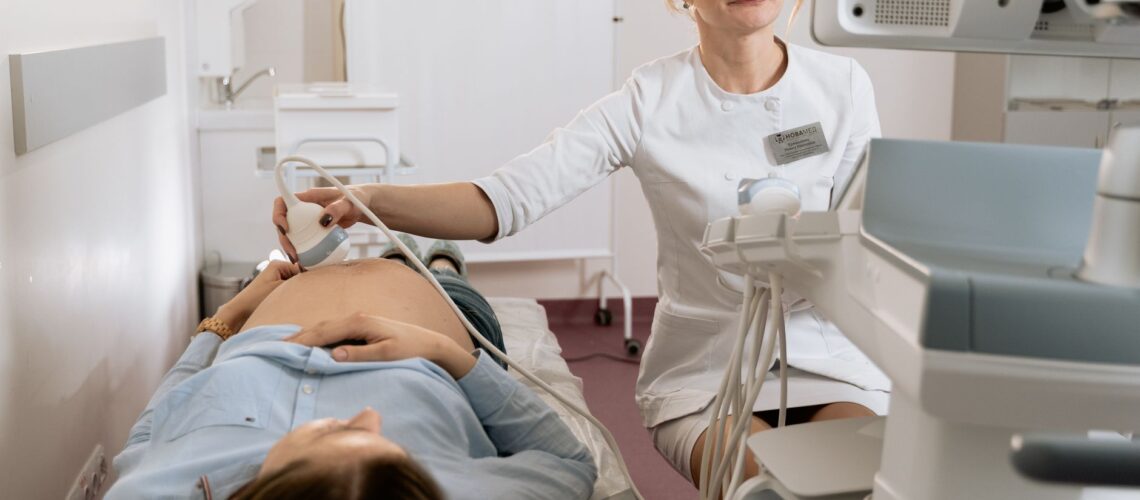 A pregnant woman receiving an ultrasound exam conducted by a healthcare professional in a medical clinic.