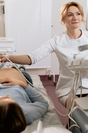 A pregnant woman receiving an ultrasound exam conducted by a healthcare professional in a medical clinic.