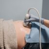 A healthcare professional performing an ultrasound on a pregnant abdomen.