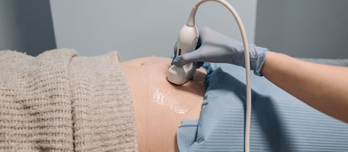 A healthcare professional performing an ultrasound on a pregnant abdomen.