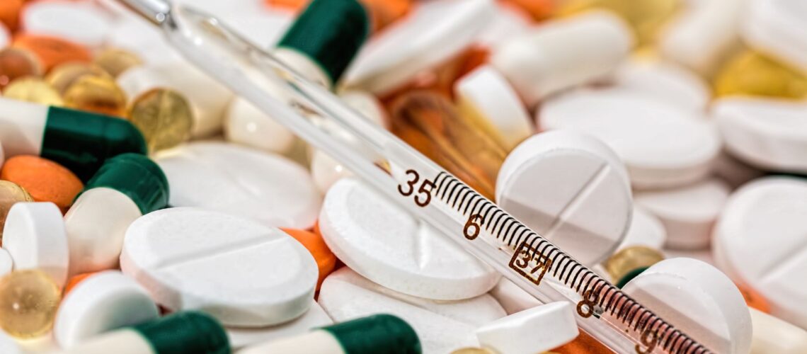 Close-up image showing various pills and a thermometer, emphasizing health and medicine.