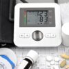 Close-up of medical equipment including blood pressure monitor, pills, and ECG printout.