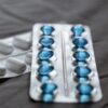 Detailed view of medication in blister packs showcasing blue softgel capsules and white pills.