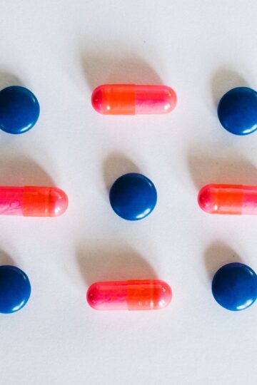 Various blue and pink pills and capsules arranged on a white background, showcasing medication.