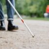 Close-up of a walking stick used by a visually impaired person in a park, symbolizing independence and mobility.