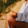 A close-up of a person meditating outdoors, capturing mindfulness at sunset on a beach.