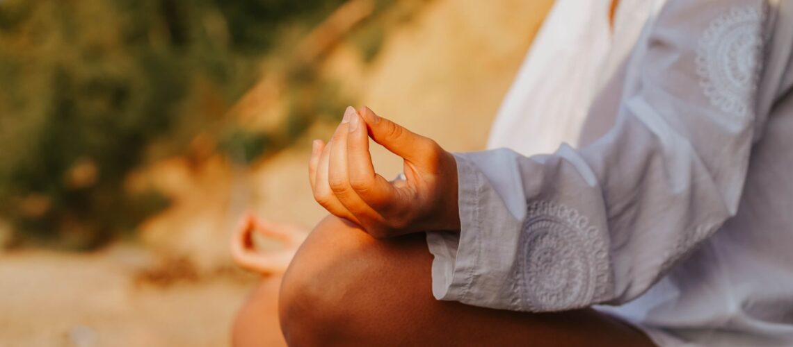 A close-up of a person meditating outdoors, capturing mindfulness at sunset on a beach.