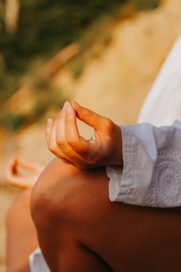 A close-up of a person meditating outdoors, capturing mindfulness at sunset on a beach.