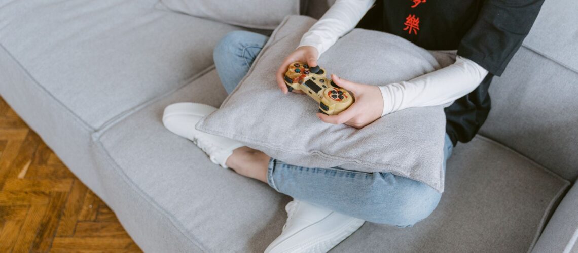 Person sitting on a couch playing video games, symbolizing leisure and entertainment.