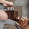 Pregnant woman doing yoga indoors with instructor assistance, emphasizing fitness and well-being.