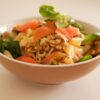 Delicious pasta salad featuring smoked salmon, walnuts, and fresh greens in a ceramic bowl.