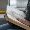Close-up of hands holding an anatomy book, studying human muscles in a train.