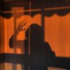 Eerie shadow of a person on an orange wall creating a mysterious vibe.