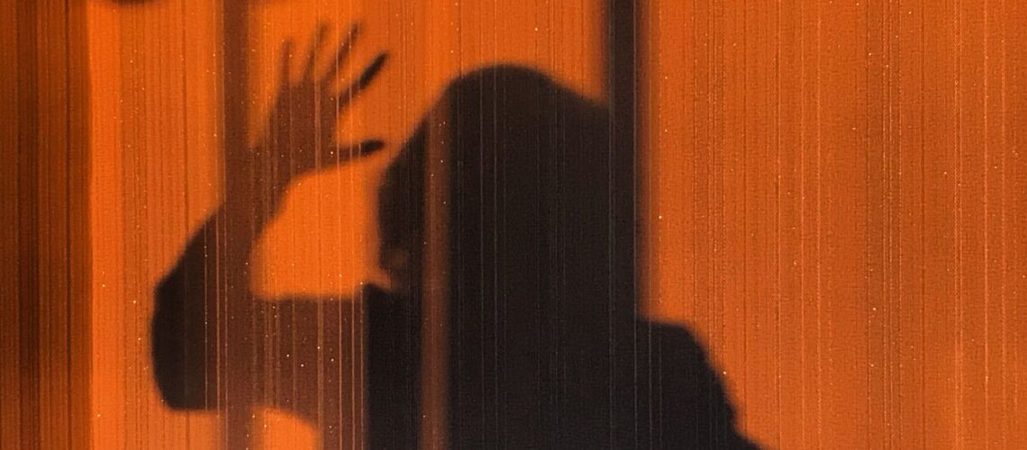 Eerie shadow of a person on an orange wall creating a mysterious vibe.