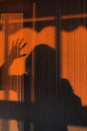 Eerie shadow of a person on an orange wall creating a mysterious vibe.