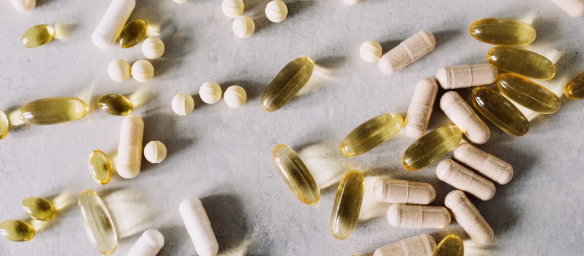 Various vitamins and supplements on a marble background, captured in flat lay style.