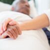 A comforting gesture as a hand holds another in a hospital setting, symbolizing care and support.