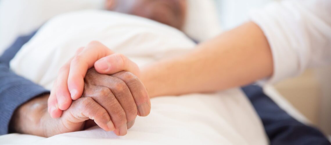 A comforting gesture as a hand holds another in a hospital setting, symbolizing care and support.