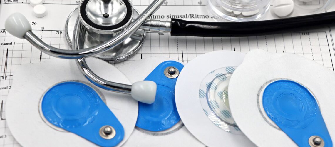 Medical instruments including stethoscope and ECG electrodes on a cardiology chart.
