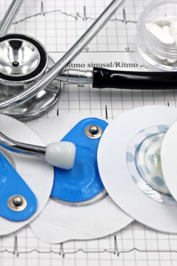Medical instruments including stethoscope and ECG electrodes on a cardiology chart.