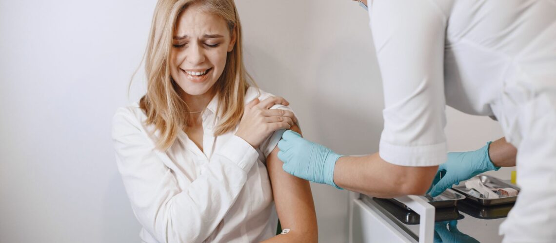 Blonde woman receives vaccination from healthcare professional indoor.