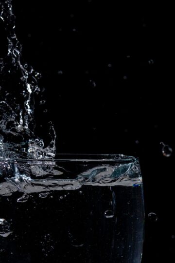 Close-up of water splashing in a glass against a black background.