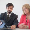 Business meeting in Portugal between a man and senior woman discussing with tablet.