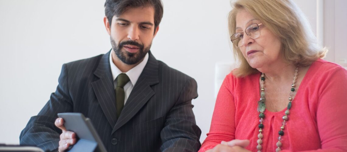 Business meeting in Portugal between a man and senior woman discussing with tablet.