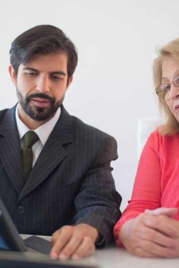 Business meeting in Portugal between a man and senior woman discussing with tablet.