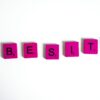 Purple Scrabble tiles spelling 'obesity' on a white surface, conceptual still life.