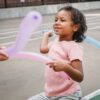 Smiling child playing with colorful balloons outdoors in a playground.