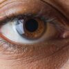 Macro shot of a human brown eye emphasizing the intricate iris details, eyelashes, and skin texture.