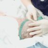 A healthcare professional measures a newborn baby's head circumference in a hospital setting.