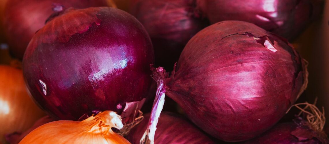 Vivid close-up shot of organic red and yellow onions with natural texture in a basket.