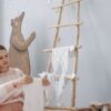 Pregnant woman arranging baby clothes in serene indoor setting with playful decor.