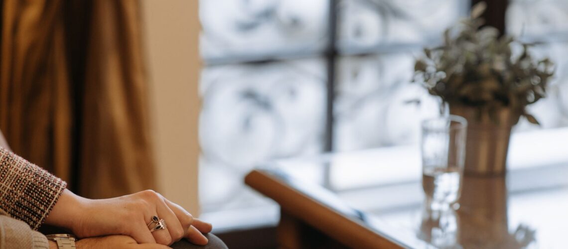 A close-up of hands in a supportive gesture on an indoor table setting, conveying warmth and care.