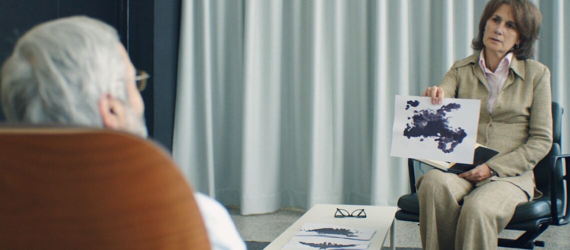 A therapist and patient in a psychotherapy session, discussing inkblot test results.