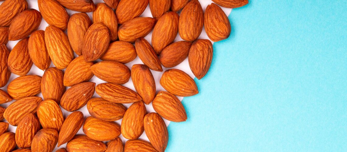 Close-up of roasted almonds arranged on a vibrant blue background, showcasing their rich texture and color.