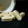 Close-up of white capsule pills spilled from a bottle on a black background. Ideal for health-related visuals.