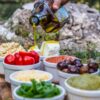 Outdoor picnic with various Mediterranean spreads, herbs, and olive oil drizzle.